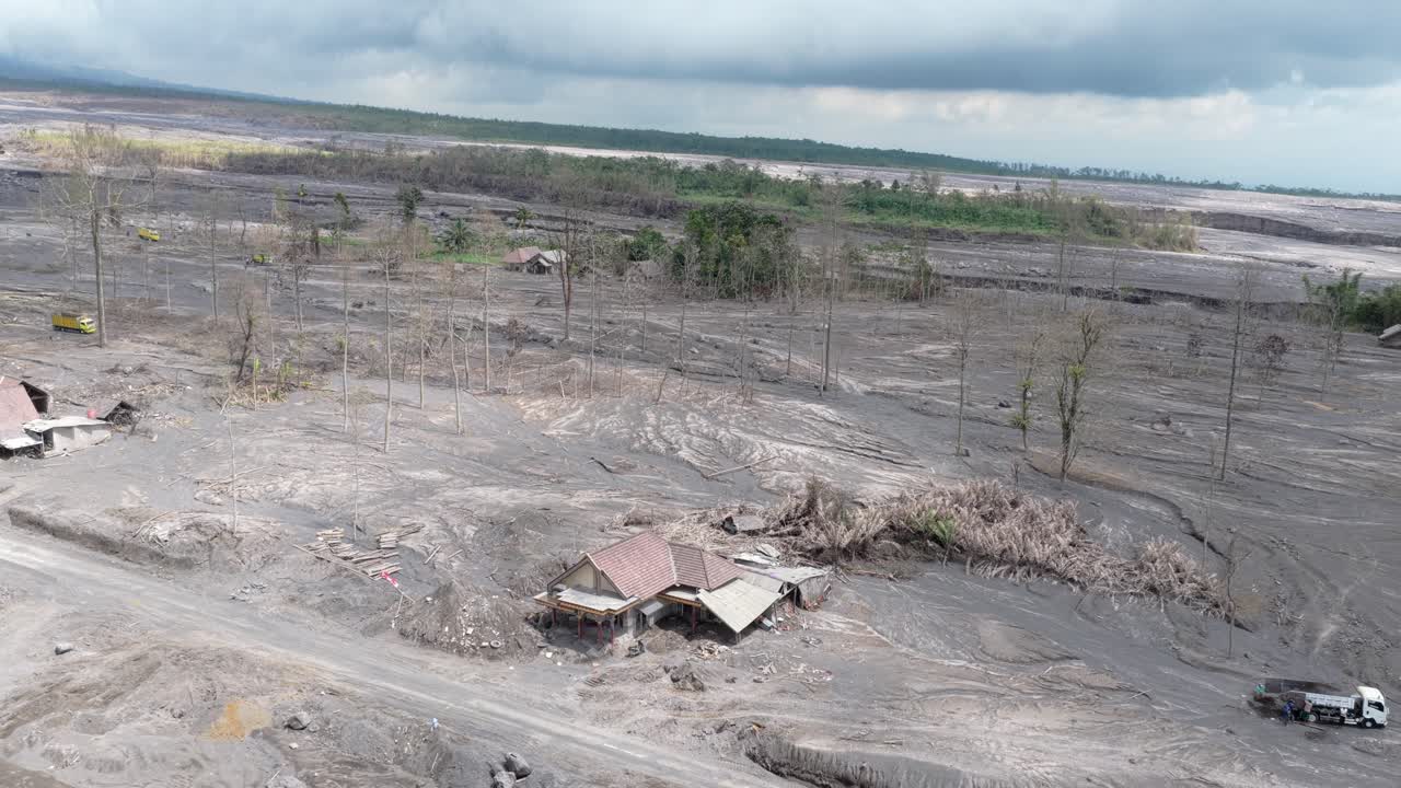 Vista aerea di un villaggio distrutto da cenere vulcanica e colate di fango lahar a seguito dell'eruzione del vulcano Semeru. Case distrutte e un paesaggio brullo.