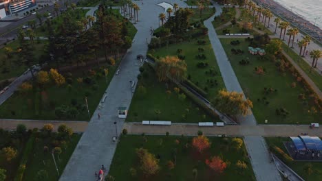 Drone-flight-above-cityscape-of-Batumi-with-modern-residential-buildings-and-natural-parkland-at-sunset