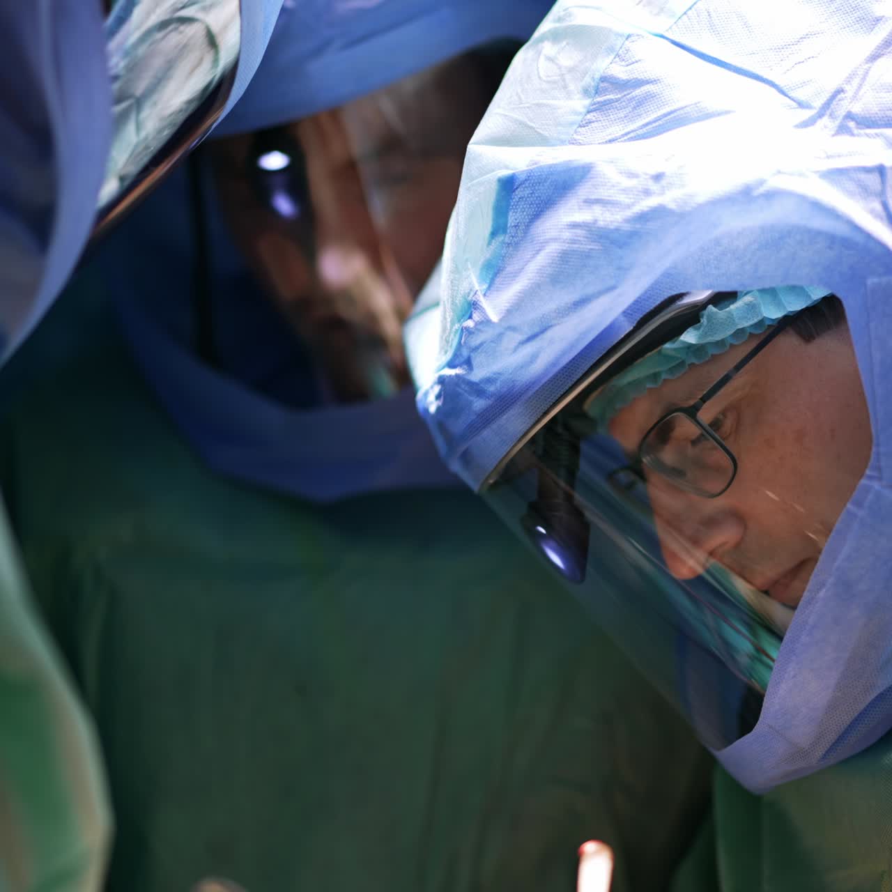 Læger med beskyttelseshjelme arbejder på en operation. Et par kirurger samarbejder om artroskopisk kirurgi.