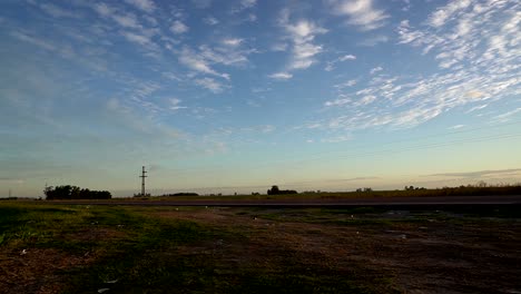 un auto blanco conduce rápido a través de una ruta al atardecer bajo un hermoso cielo con nubes