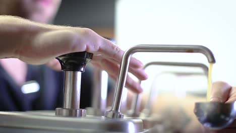 employee pumping sauce measurement for recipe.