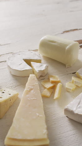 video vertical de algunos tipos de queso sobre un fondo rústico blanco