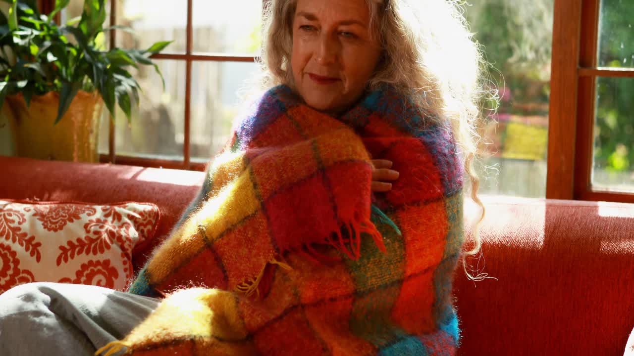 mujer madura envuelta en una manta en casa 4k