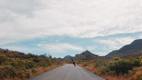 young man using longboard skating fast enjoying cruising downhill on beautiful countryside road riding skateboard slow motion