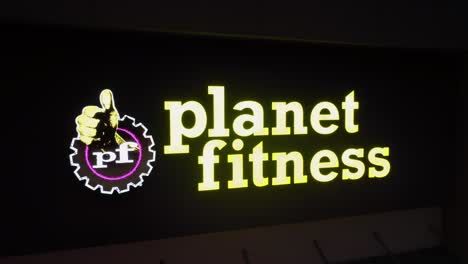 aerial approaching shot of planet fitness building at dusk. fitness gym in american town at night. lighting sign on modern architecture.