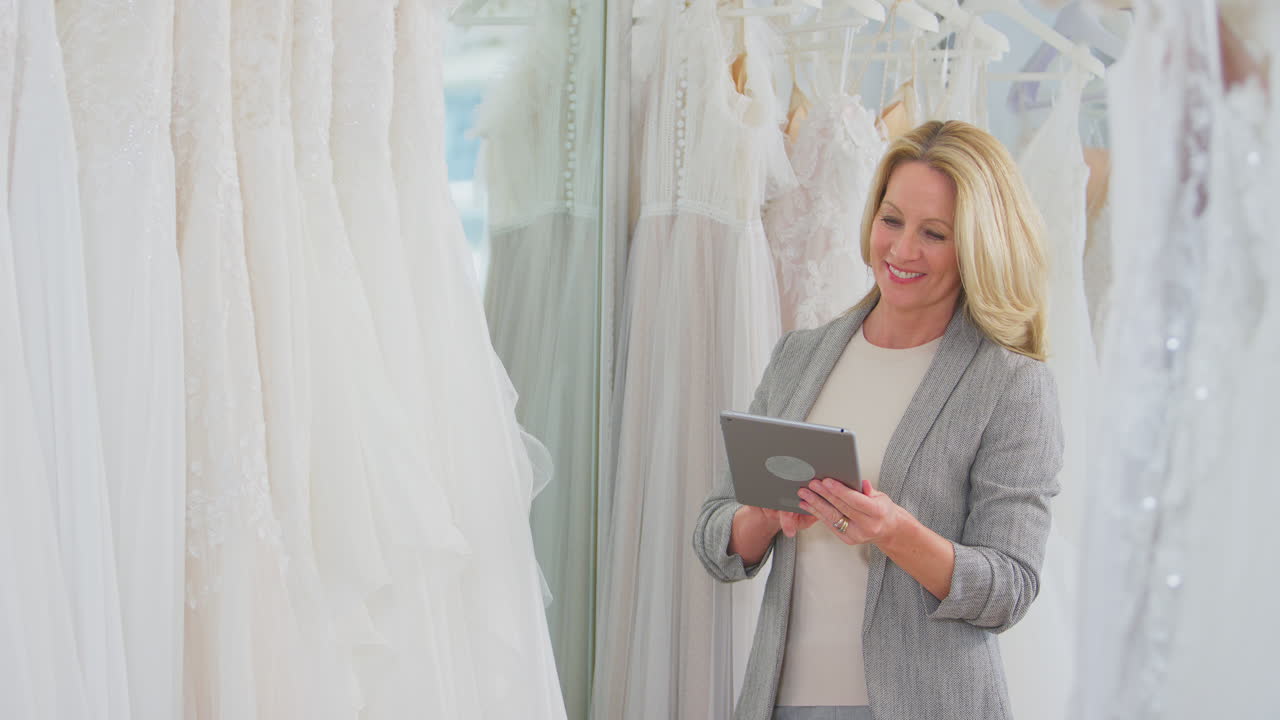 디지털 태블릿과 함께 신부 웨딩 드레스 가게의 성숙한 여성 소유자
