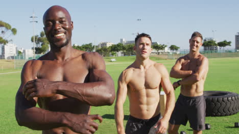 tres hombres en forma diversos sin camisa sonriendo y dirigiéndose a la cámara después de hacer ejercicio al aire libre
