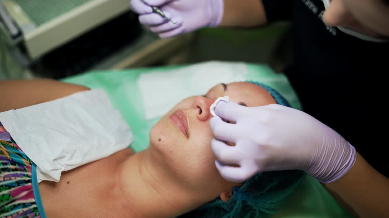 Pore cleansing in the beauty salon. Caucasian female is having the procedure of blackheads removal with the help of cosmetologist tool. Top view.