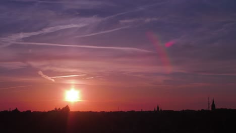 time lapse of beautiful scenic red sunset over the city with sun shining through the clouds with sun flare, wide shot