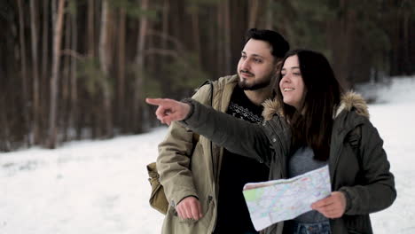 Kaukasisches-Paar,-Das-In-Einem-Verschneiten-Wald-Auf-Der-Karte-Nach-Wegbeschreibungen-Sucht.