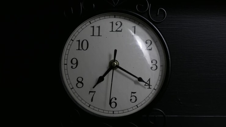 Time-lapse of a small black clock in a dimly lit room
