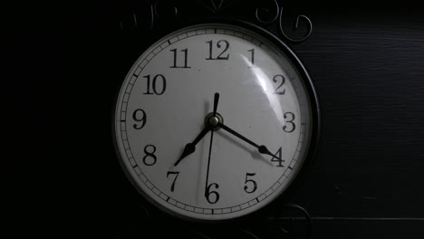 time-lapse of a small black clock in a dimly lit room