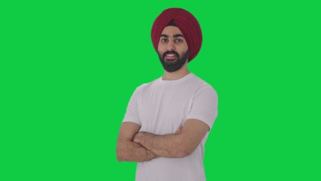 portrait of happy sikh indian man standing crossed hands green screen