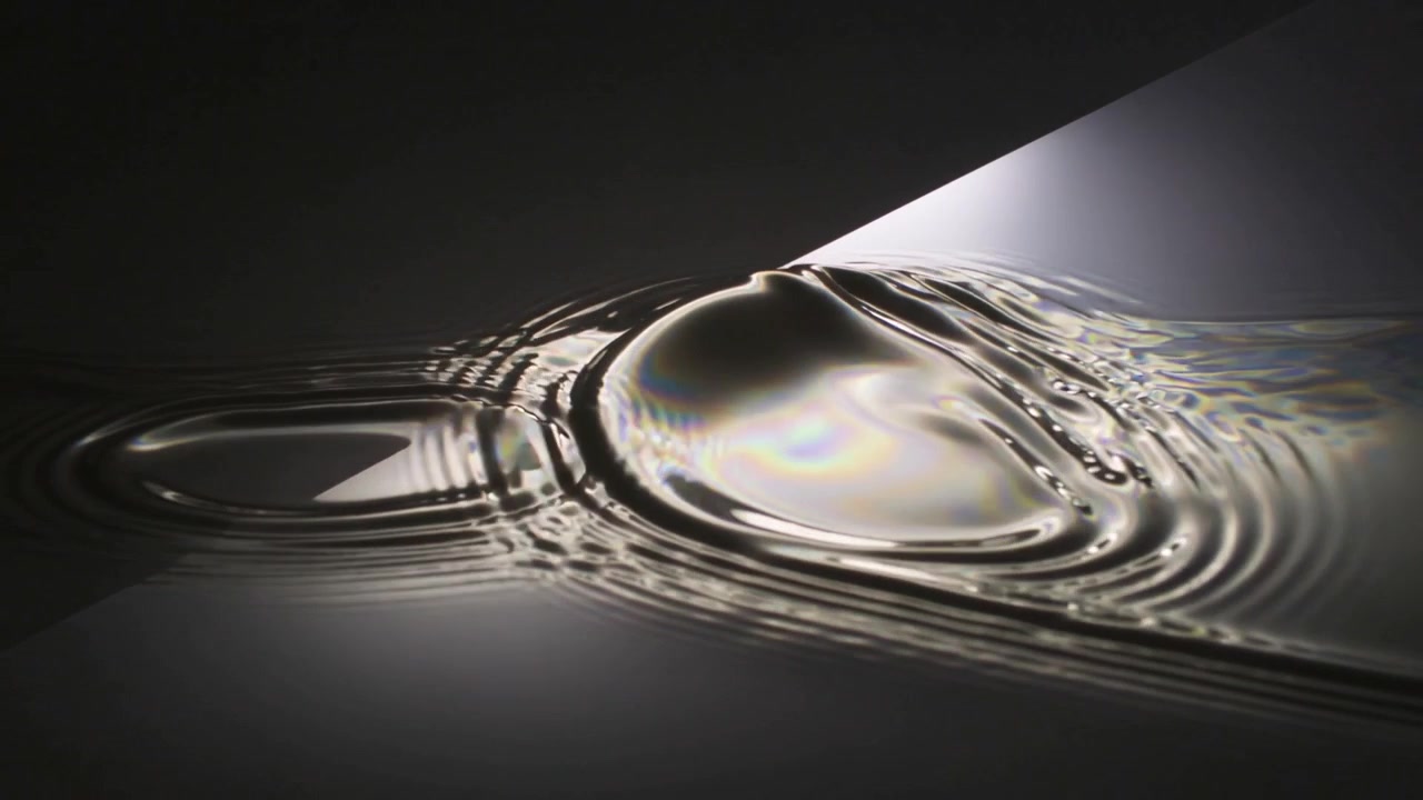 Initial localized disturbance sending rings and forming dome on film, dark studio, diagonal light