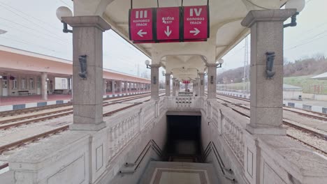 train station platform information signs leads down stone staircase to tunnel