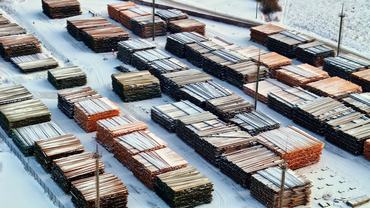 Vista elevata di legname impilato e assi di legno disposti in file in un deposito di legname innevato