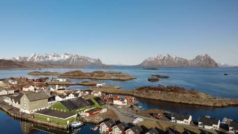 aerial drone shot of cottages in lofoten norway with big mountains in the background. surrounded by the ocean