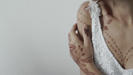 mujer con intrincados diseños de henna en sus manos y pecho