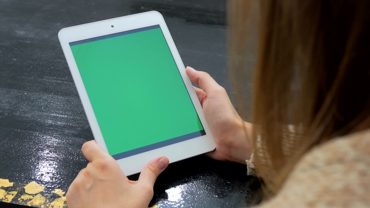mujer mirando una tableta con pantalla verde