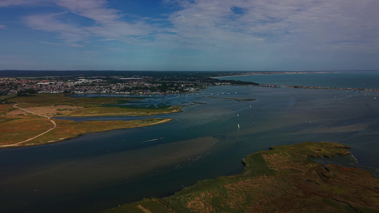 Tomas aéreas sobre Hengistbury Head en Dorset, Inglaterra, que muestran brezales, bosques, senderos y aguas protegidas del puerto junto a los acantilados costeros. La toma destaca la mezcla de actividades recreativas