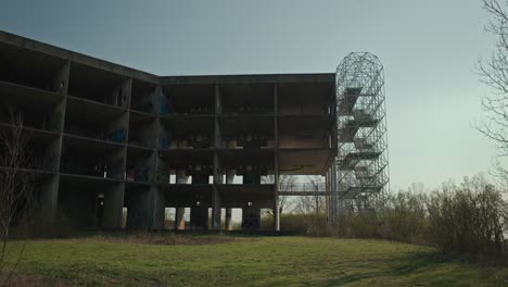 Abandoned-University-Hospital-in-Zagreb,-a-skeletal-concrete-structure-amidst-overgrown-greenery,-under-a-serene-sky