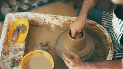 an unrecognisable man working with clay