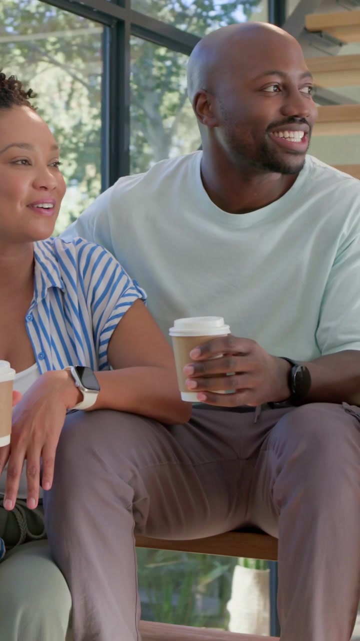 Vertical video: Chatting couple with woman starting planning on wood stairs holding to-go cups