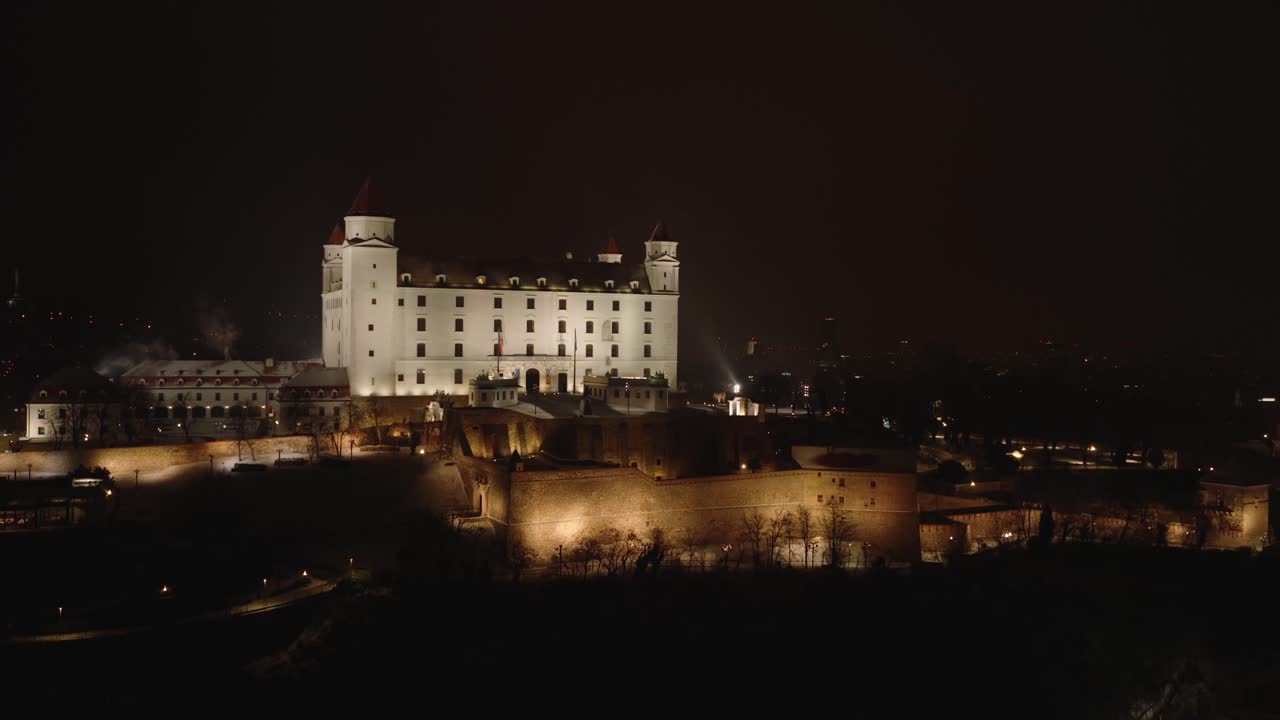 Vista aerea notturna del Castello di Bratislava illuminato d'inverno, con vista sullo skyline della città. Monumento storico, atmosfera innevata, architettura europea, atmosfera serena serale