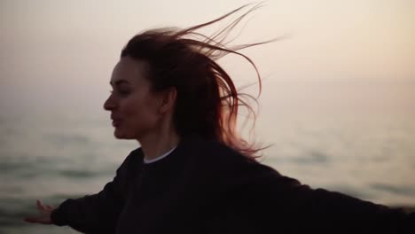 a woman runs happily along the autumn seashore spreading hands with sunshine on the background