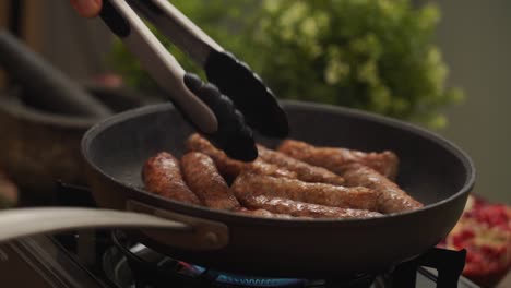 persona de la cosecha girando salchichas caseras fritando en sartén