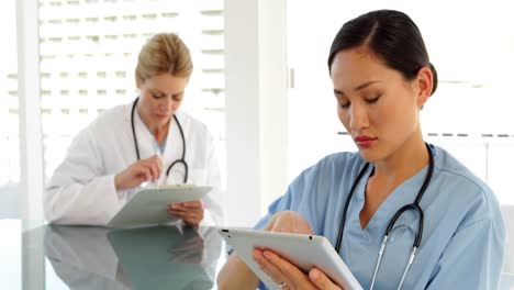 Medical-workers-sitting-at-desk-using-tablet