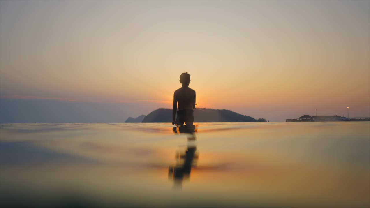 Silhouette of a person in water at sunset