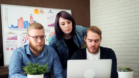 team working with the laptop while sitting at the desk in creative office