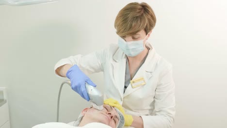 professional face skin rejuvenation, lifting procedure. cosmetologist uses modern ultrasound device. hardware cosmetology