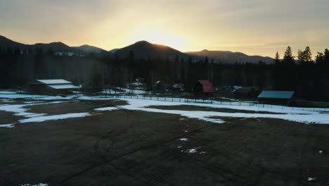 Aerial-orbit-of-snowy-farmland-ranch-at-sunset