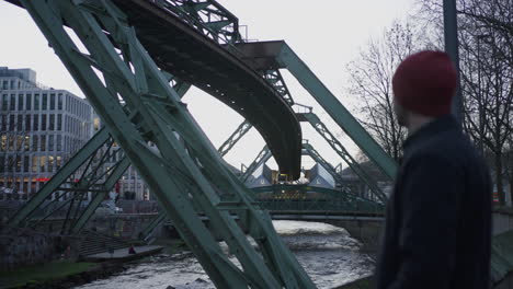 young man admiring wuppertal's suspended railway system in germany