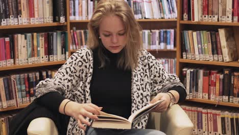 toma panorámica de una niña leyendo un libro en la biblioteca.