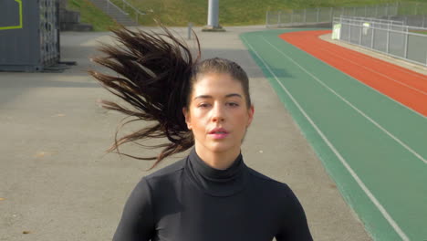 beautiful athletic woman running on the track, frontal shot, dolly out