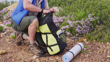 Älterer-Wanderer,-Der-Beim-Trekking-In-Den-Bergen-Ein-Fernglas-Aus-Dem-Rucksack-Holt.