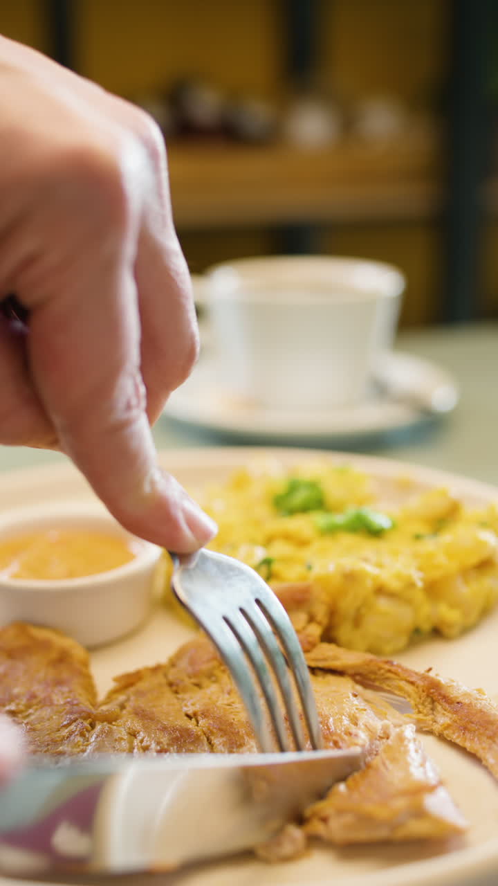Close-up of a fork and knife cutting tender meat accompanied by mote pillo and sauce