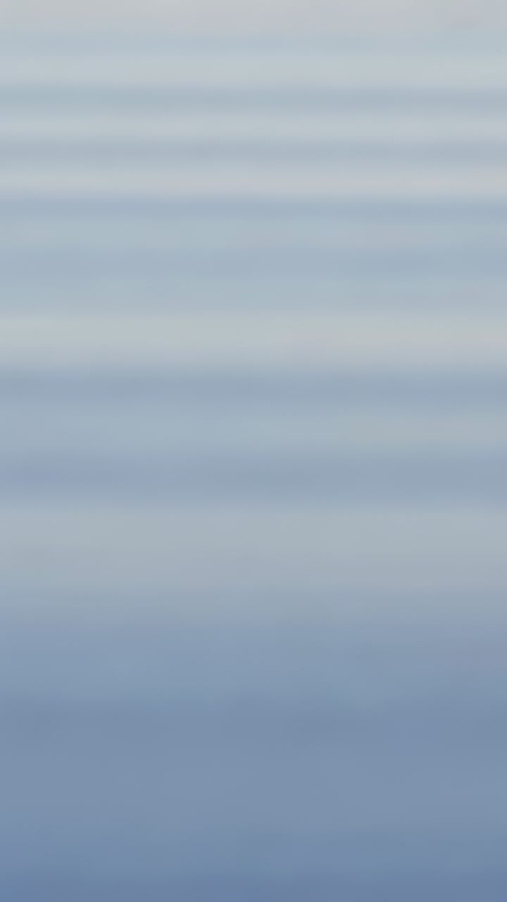 Vertical video: Passing wave stirring surface in tank, drops forming crown, rebound jets, ripples