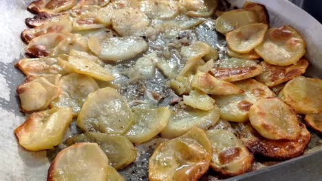 bandeja llena de rebanadas de patatas asadas en la parte superior del papel para hornear