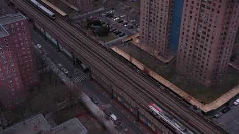 stationary aerial shot over crossing commuter trains through housing projects in harlem new york city