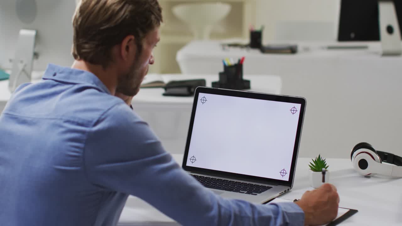 hombre de negocios caucásico teniendo una reunión de videollamadas usando una computadora portátil y tomando notas