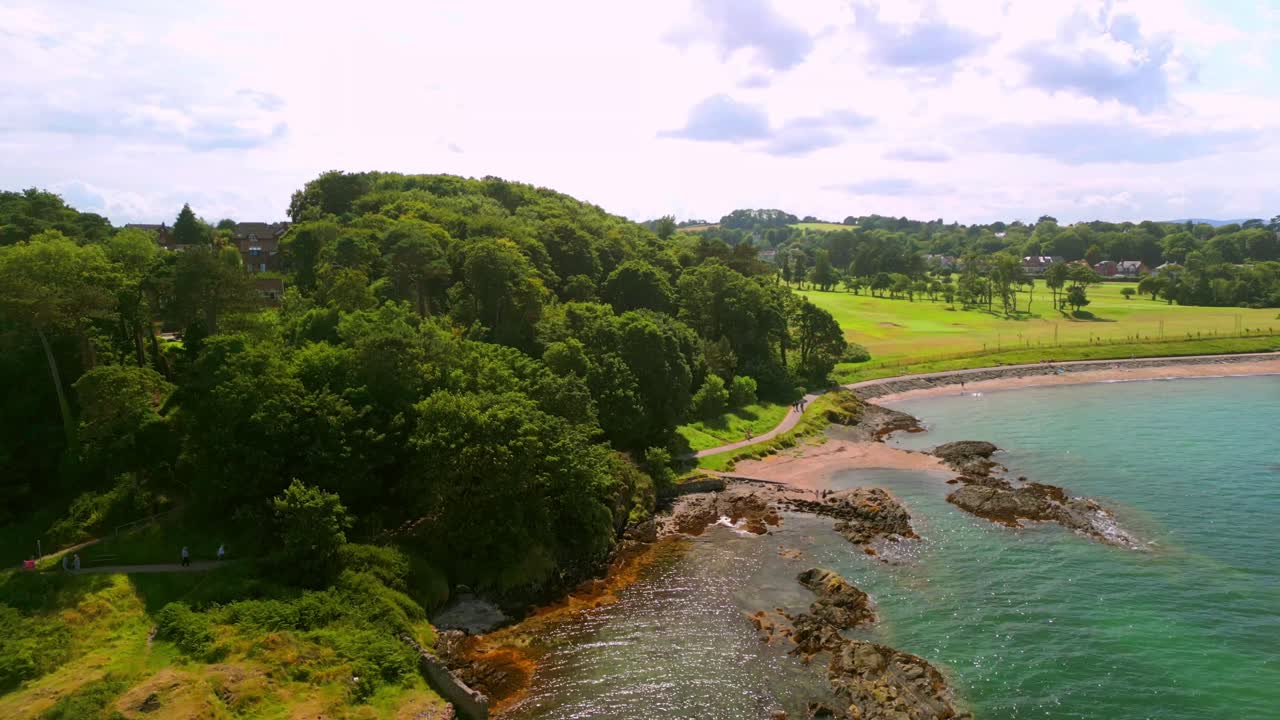 Wkde reversing aerial video of Helen's Bay beach in County Down, Northern Ireland, UK on a bright summer day. Filmed in 4K, 60FPS and with Rec709 color