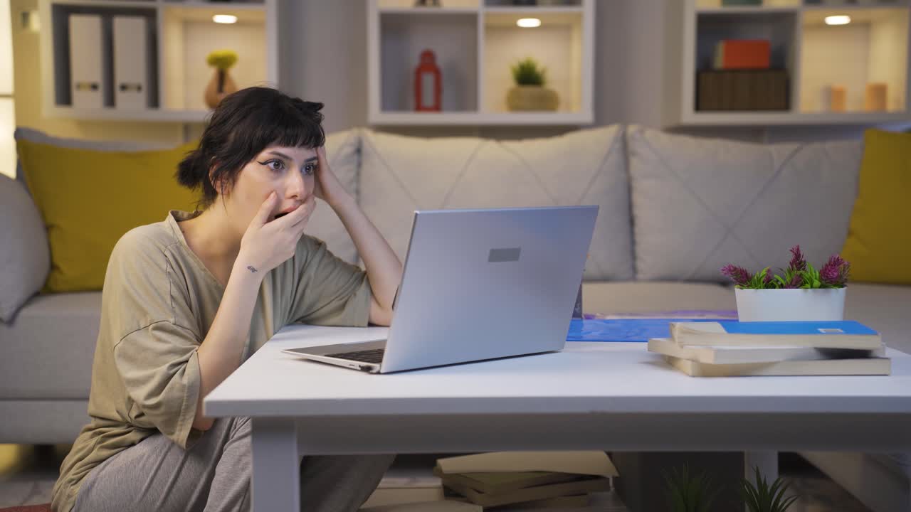mujer joven mirando la computadora portátil con sorpresa por la noche en casa. sorprendido por lo que vio en la computadora portátil.