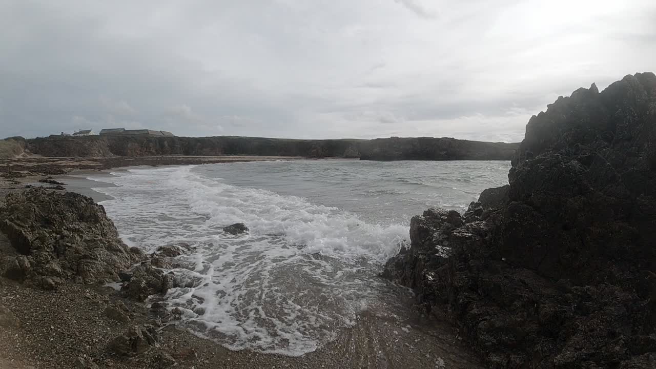 Onde oceaniche che si infrangono su una grande costa rocciosa ad Anglesey, al rallentatore.
