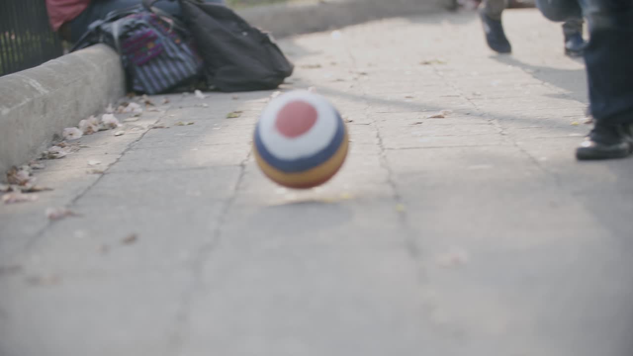 imágenes en cámara lenta de un niño persiguiendo una pelota rayada en una plaza en antigua, guatemala