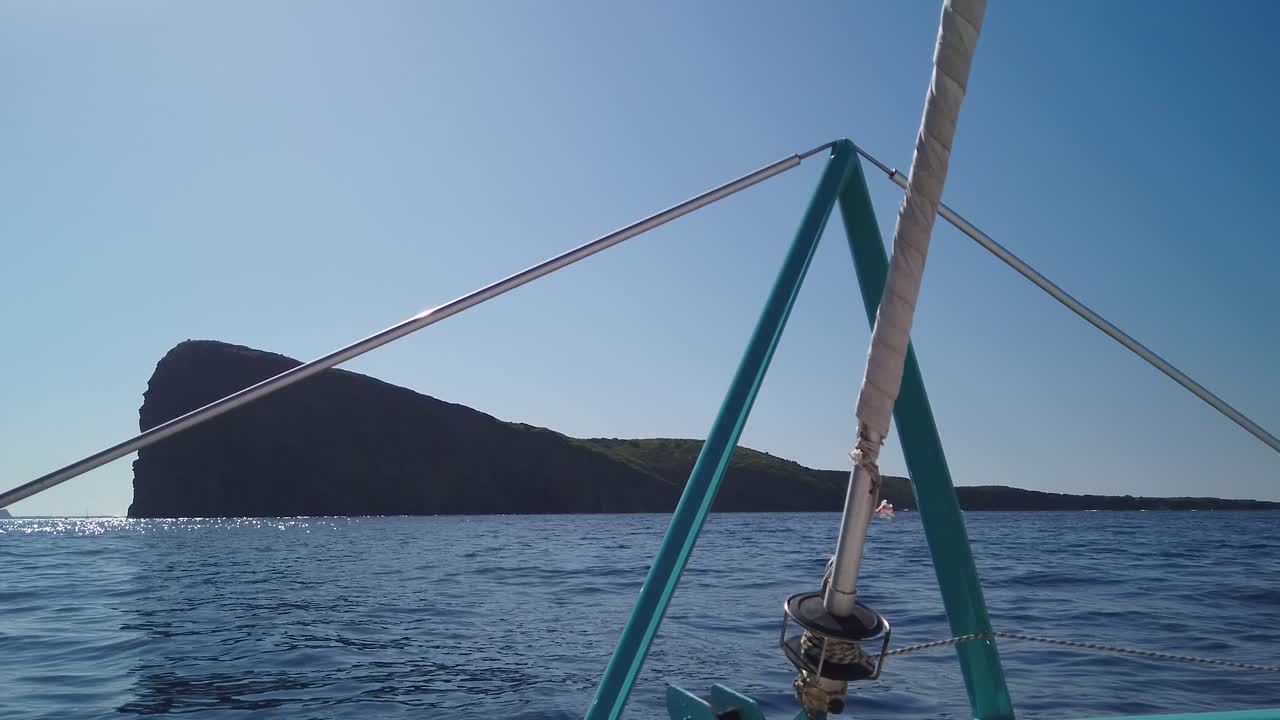 una toma enfocada en una isla, tomada desde la proa del catamarán, avanzando hacia la isla