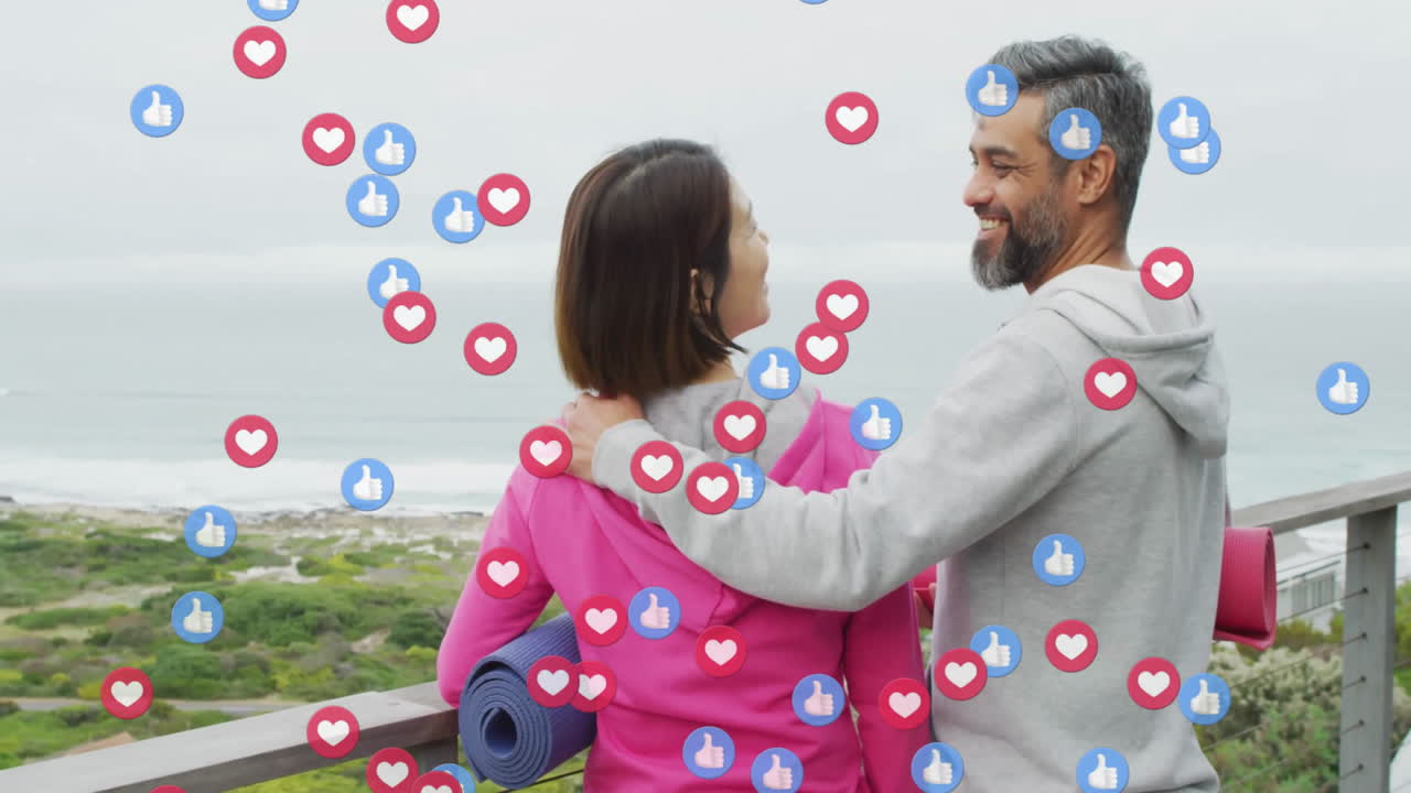 animación de iconos emoji sobre una pareja diversa sosteniendo esteras de yoga